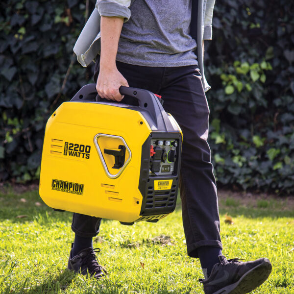 Man carrying Yellow and black 'The Mighty Atom' Champion 92001i Inverter Petrol Generator.